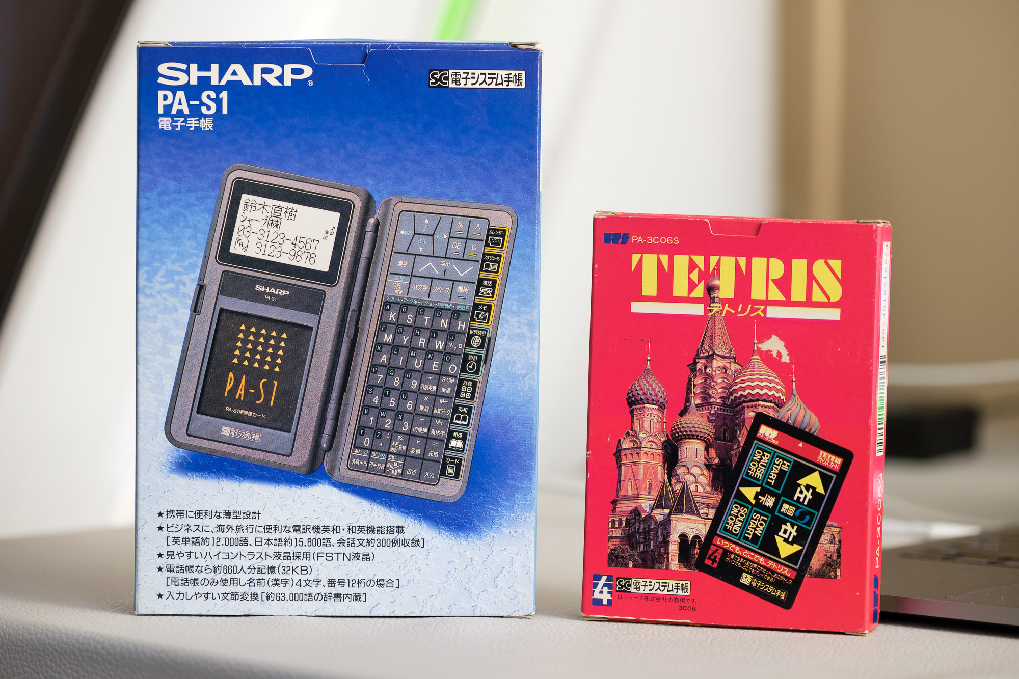A photo with two boxes standing upright on a table. The first box is of a Sharp PA-S1, an obsolete PDA. The second box is for the game Tetris for Sharp PDA devices like the one next to it.