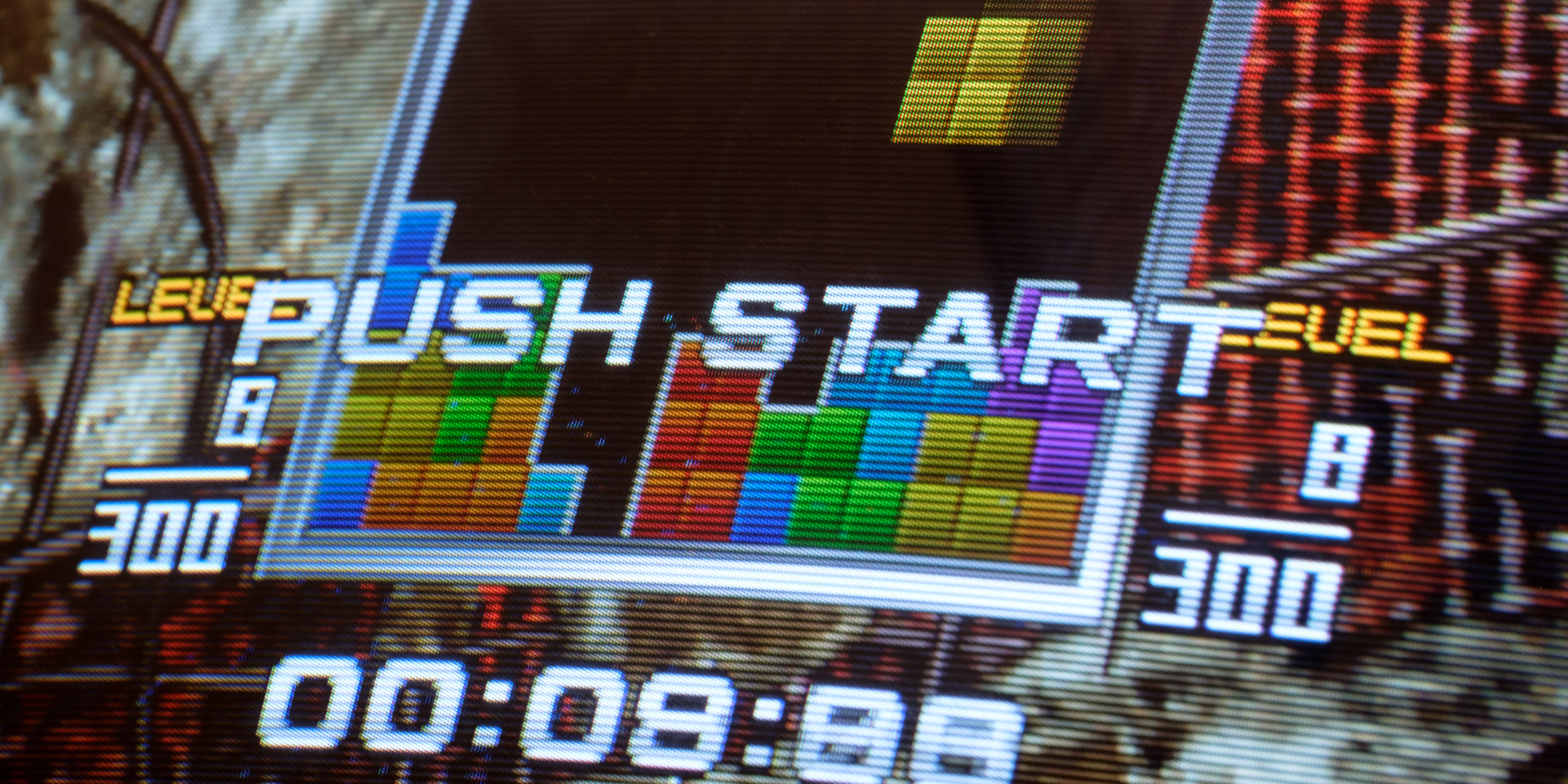 An very cropped in photo of a CRT arcade monitor showing the Tetris: The Absolute - The Grand Master 2 PLUS attract mode.