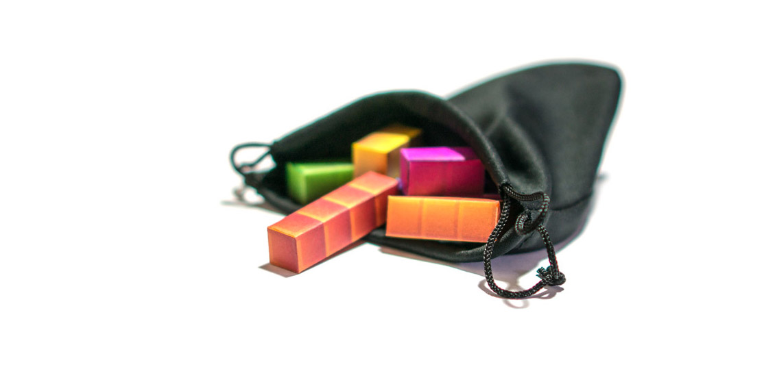 A small black bag with some papercraft tetrominoes spilling out. The tetrominoes are colored the same as a Tetris game.
