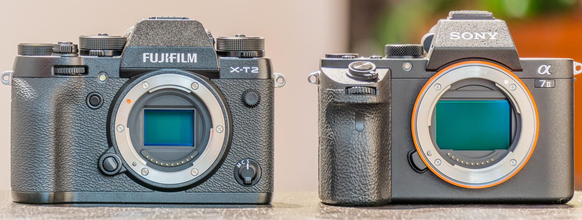 Two cameras side by side, a Fujifilm X-T2 and a Sony a7 mark 2, with their lenses removed exposing the image sensor of each camera.